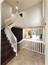 Foyer featuring high ceilings, wood-finish staircase treads, white balustrades, large-format tile flooring, and sliding glass doors