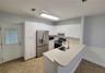 Kitchen featuring white cabinetry, stainless steel appliances, a peninsula with a stainless steel sink, and tile flooring