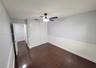 Interior room featuring dark wood-finish flooring, two-tone walls with chair rail molding, a sliding-door closet, and an attached ceiling fan with int