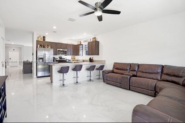 Open concept interior featuring polished tile flooring, dark wood-finish cabinetry, stainless steel appliances, a peninsula with stone-finish countert