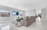 Neutral-toned interior featuring large-format tile flooring, recessed ceiling lighting, and windows equipped with dual-shade treatments