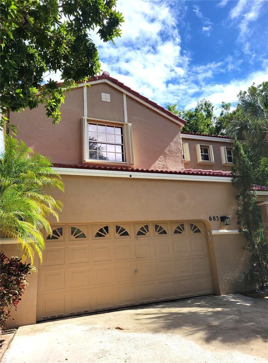 Stucco exterior featuring a dual-pitch tile roof, arched-top garage door panels, and decorative trim shutters