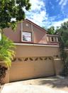 Stucco exterior featuring a dual-pitch tile roof, arched-top garage door panels, and decorative trim shutters