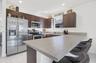 Kitchen featuring dark wood cabinetry, stainless steel appliances, wood-finish breakfast bar, and light-toned tile flooring