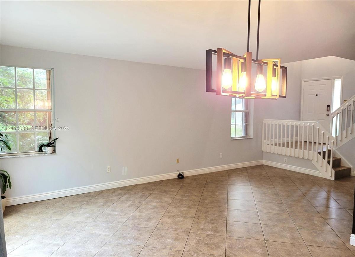 Tile flooring, multi-light rectangular pendant fixture, grid-pattern windows, and staircase with white railings