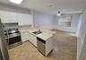 Kitchen featuring white cabinetry, neutral-toned countertops, stainless steel appliances, a double-basin undermount sink with a gooseneck faucet, and 