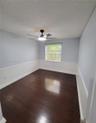 Room featuring wood-finish flooring, white wainscoting, a single-hung window, and an integrated ceiling fan with light fixture