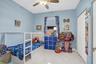 Room featuring polished stone-finish tile flooring, a centered ceiling fan with integrated light fixture, and double-door closet storage