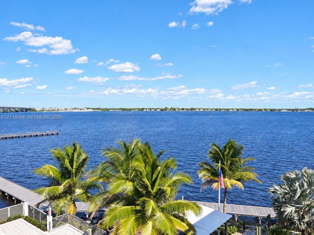 Waterfront property featuring a private dock, expansive deck, and mature palm trees