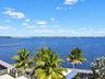 Waterfront property featuring a private dock, expansive deck, and mature palm trees