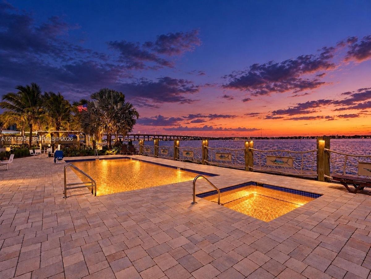 Paver patio featuring a swimming pool, integrated spa, and nautical-inspired wood post railing with rope accents