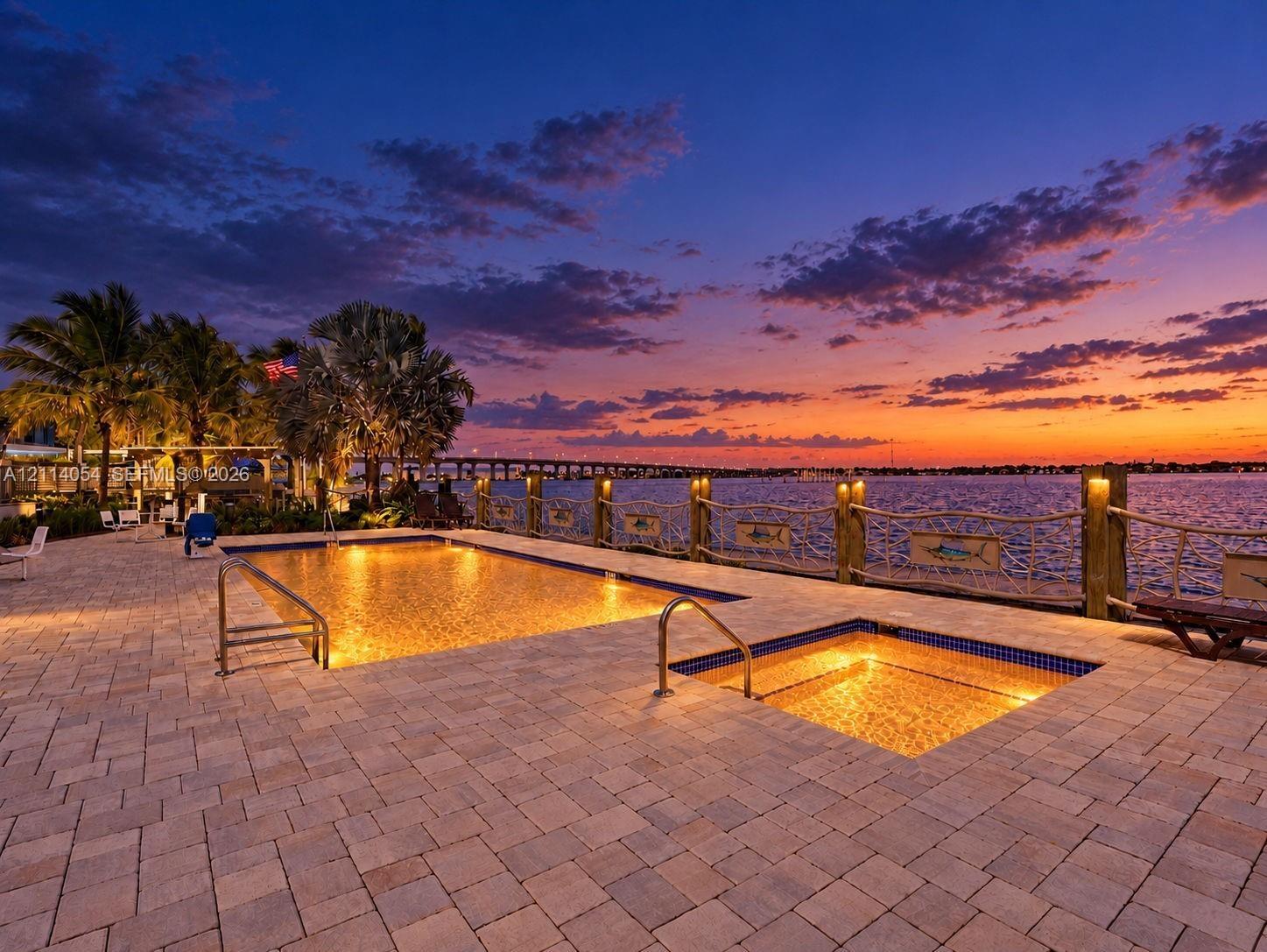 Paver patio featuring a swimming pool, integrated spa, and nautical-inspired wood post railing with rope accents