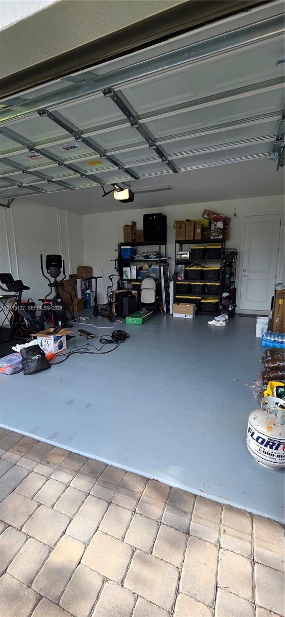 Garage featuring painted concrete flooring, a sectional overhead door, and a dedicated service door