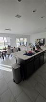 Kitchen featuring a center island with a stone countertop, dark cabinetry, recessed ceiling lighting, and tile flooring throughout