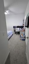Neutral-toned wall-to-wall carpeting, ceiling fan with integrated lighting, and built-in corner shelving