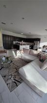 Open-concept area featuring large-format tile flooring, recessed ceiling lighting, and a kitchen equipped with dark cabinetry, a central island, and s