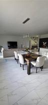Large-format tile flooring with a neutral veined finish, multi-light linear pendant fixture, and white cabinetry