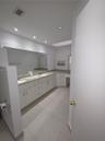 Bathroom featuring a dual-sink vanity with stone countertops, white cabinetry, a skylight, and tile flooring