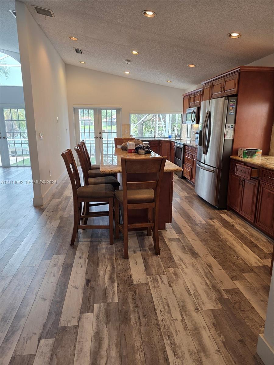Kitchen featuring wood-finish flooring, recessed lighting, stained wood cabinetry, stone-finish countertops, and stainless steel appliances