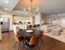 Open-concept kitchen featuring high-gloss cabinetry, stainless steel refrigerator, breakfast bar with waterfall-edge countertop, recessed lighting, an