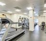 Fitness center featuring grid ceiling lighting, wall-to-wall mirrors, and resilient rubberized flooring