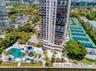 High-rise condominium tower featuring a resort-style swimming pool, multiple tennis courts, private marina access, and landscaped grounds