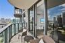 Private balcony with glass panel railing, wood-finish flooring, and floor-to-ceiling sliding glass doors