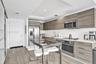 Kitchen featuring wood-finish cabinetry, solid surface countertops, stainless steel appliances, recessed ceiling lighting, and wood-finish flooring