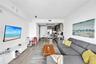 Open-concept interior featuring wood-finish flooring, kitchen with stainless steel appliances, flat-panel cabinetry, and integrated ceiling lighting
