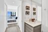 Bathroom featuring a vanity with wood-finish cabinetry, integrated countertop, oval undermount sink, and full-height wall mirror