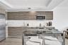 Kitchen featuring wood-finish cabinetry, stone-surface countertops, stainless steel appliances, recessed ceiling lighting, and wood-finish flooring