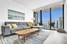 Floor-to-ceiling windows, wood-finish flooring, and a private balcony with metal railing