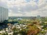 Elevated cityscape featuring expansive tree canopy, high-rise architectural silhouettes, and integrated surface parking