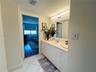Vanity featuring a solid-surface countertop, integrated oval sink, chrome dual-handle faucet, white cabinetry with crystal-style hardware, and a full-