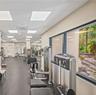 Fitness center featuring rubber flooring, recessed panel lighting, and large windows with exterior landscaping exposure