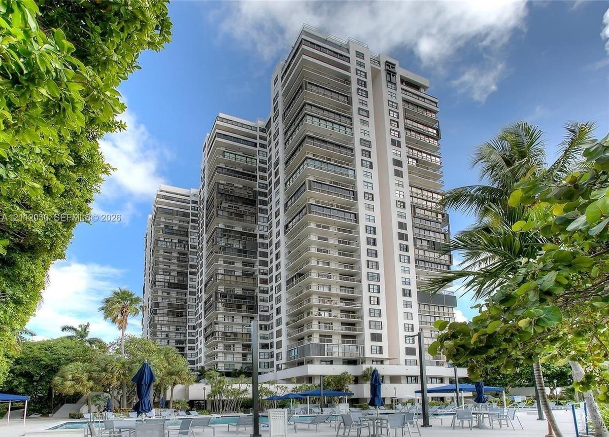High-rise residential tower featuring tiered balconies, expansive glass window walls, paved outdoor deck, and integrated swimming pool