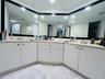 L-shaped dual vanity featuring white cabinetry, polished metal hardware, expansive wall-to-wall mirrors, and dual chrome faucets