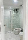 Glass block shower partition, walk-in shower with rainfall showerhead, ceramic tile walls, and bidet