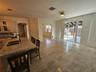 Kitchen featuring a stone-topped island with an integrated double-basin sink and high-arc faucet, neutral tile flooring, arched doorways, and sliding 
