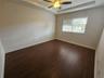 Interior space featuring dark wood-finish flooring, a tray ceiling, and an integrated ceiling fan with light fixture