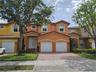 Two-story residence featuring a tile roof, stucco exterior, double-entry doors, and a paver driveway leading to a two-car garage