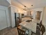 Kitchen featuring white cabinetry, stone-finish countertops, center island with a dual-basin undermount sink, stainless steel appliances, and tile flo