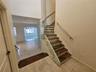 Staircase featuring dark stone treads, glass panel railings, and a metallic handrail, complemented by large-format tile flooring and high ceilings