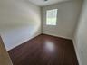 Room featuring wood-finish flooring, a single-pane window with horizontal blinds, and an attached ceiling fan