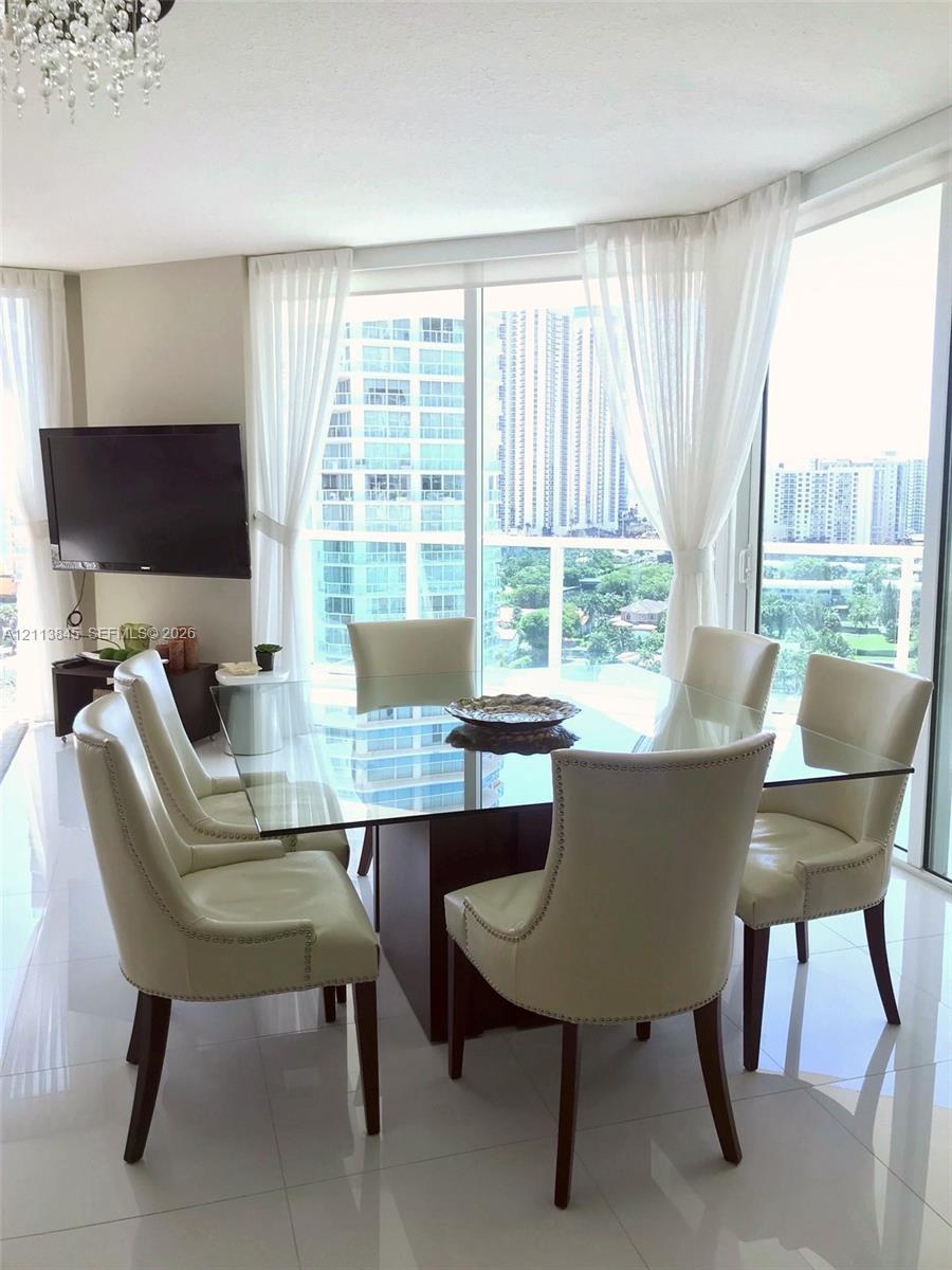 Floor-to-ceiling glass paneling, polished tile flooring, crystal chandelier, and wrap-around window configuration