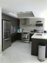 Kitchen featuring dark wood cabinetry, white stone-surface countertops, stainless steel appliances, a stainless steel chimney-style range hood, and po