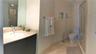 Bathroom featuring a vanity with a stone countertop, an integrated sink with a chrome faucet, full-width mirror, tile flooring, and a glass-enclosed s
