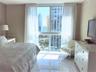 Floor-to-ceiling windows featuring urban and ocean scenery, high-gloss tile flooring, and neutral wall tones