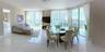 Open-concept living and dining area featuring polished tile flooring, floor-to-ceiling glass sliding doors, and a crystal chandelier