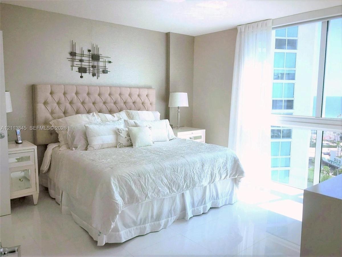 Floor-to-ceiling windows featuring exterior maritime scenery, paired with polished neutral-toned tile flooring